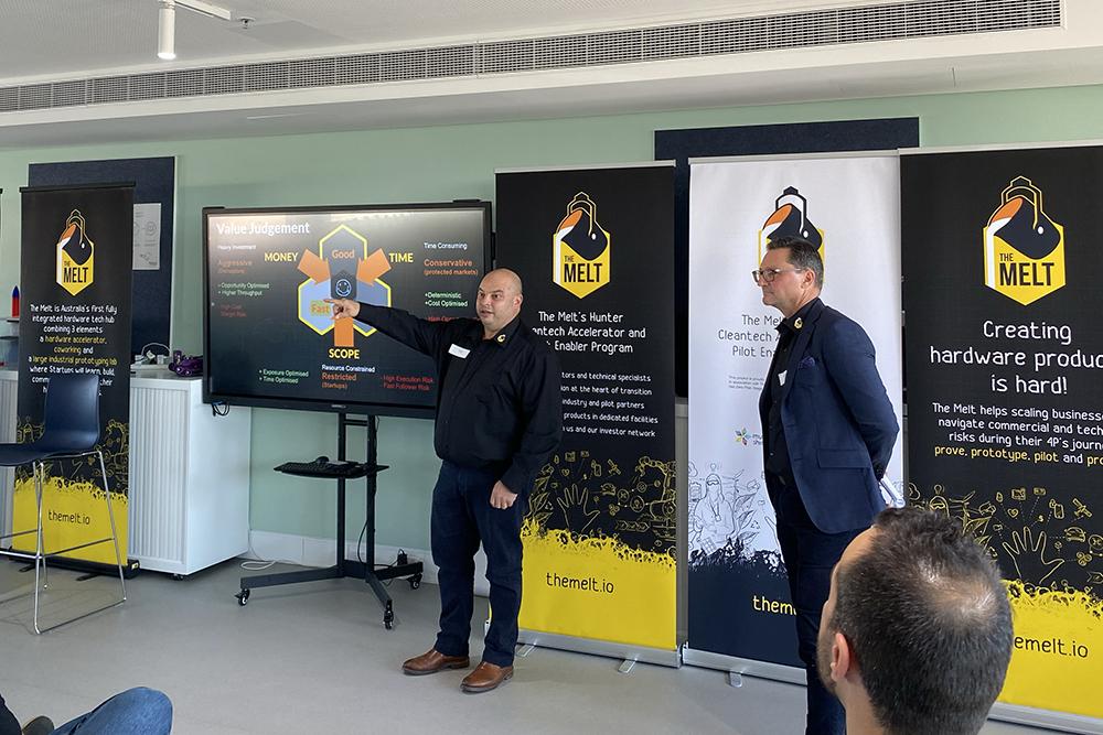 Two men presenting in front of a screen and 'The Melt' banners