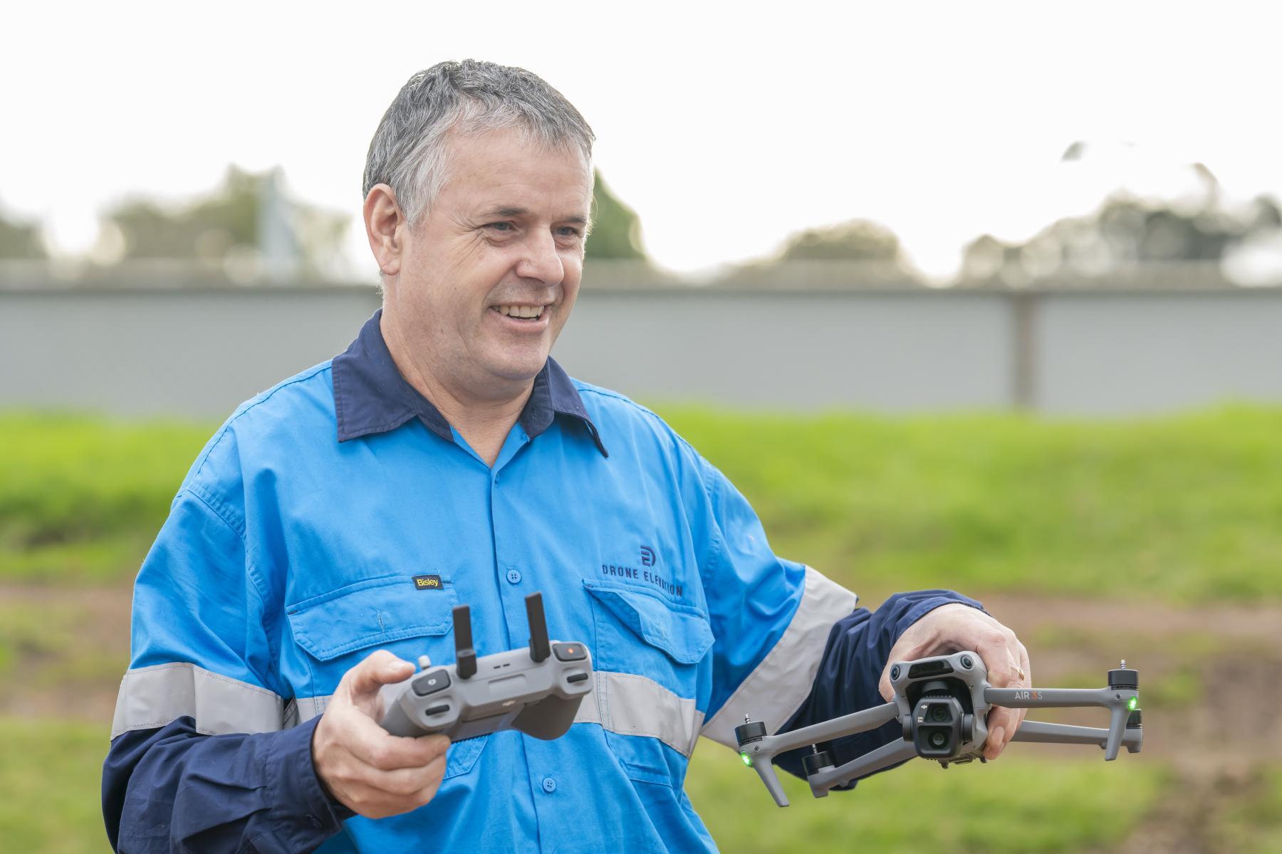 Man in blue shirt holds drone.&nbsp;