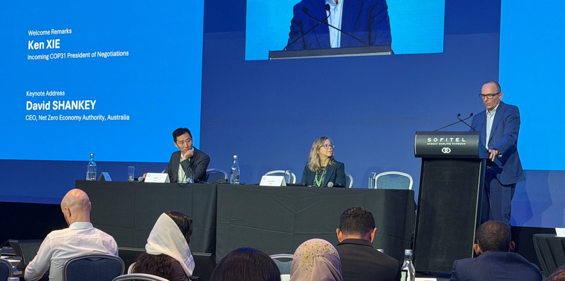 David Shankey at a lectern presenting in front of an audience and panelists