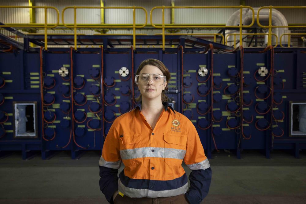 A woman in high vis gear standing in an industrial environment.